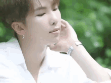 a close up of a young man wearing a white shirt and a watch .