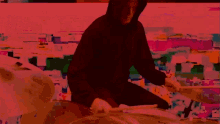 a man in a black hoodie playing drums in front of a colorful background