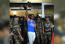a man holding a trophy wearing an india champion shirt