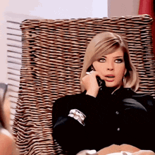 a woman is sitting in a chair talking on a cell phone