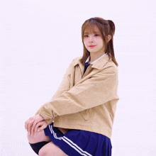 a girl wearing a tan jacket and a blue skirt is kneeling down