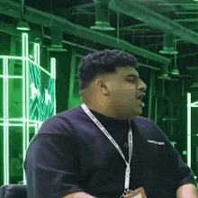 a man wearing a lanyard and a black shirt is sitting in a chair .
