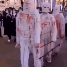 a group of people dressed as zombies with blood on their bodies are walking down a street .