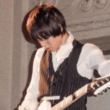 a man in a vest is playing an electric guitar