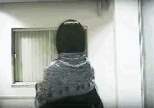 a woman is standing in front of a window in a room with a scarf around her neck .