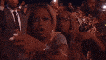 a crowd of people are standing in a dark room and applauding .