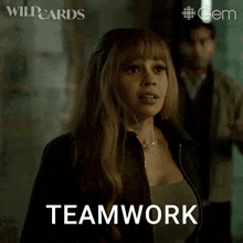 a woman is standing in front of a man and the word teamwork is on the screen