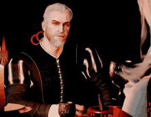 a man with a beard is sitting at a table with a cup in his hand .