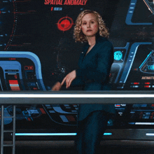 a woman stands in front of a display that says spatial anomaly