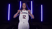 a woman wearing a white uconn jersey with the number 12