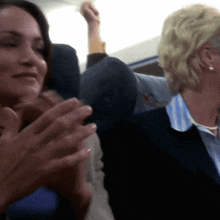 a woman applauds while another woman holds her arm up in the air