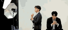 two men in suits are posing for a picture in front of a white background .