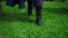 a woman in a blue dress and black boots is walking on the grass .