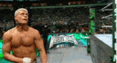 a shirtless wrestler is standing in front of a wrestlemania sign .