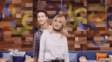 a man and a woman are standing next to each other in front of a colorful wall .