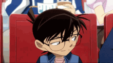 a boy with glasses is sitting in a red seat