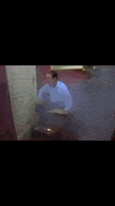 a man in a pink shirt is standing in a room with a painting on the wall