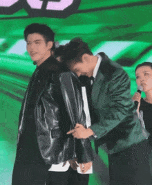 a man in a green jacket is hugging a man in a black jacket