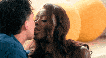 a man kisses a woman on the cheek in front of balloons