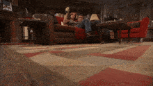 a man and a woman sit on a couch in a living room with a rug