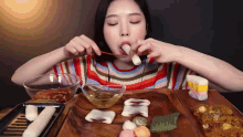 a woman in a striped shirt is eating a candy bar with a spoon