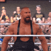 a man with a beard is standing in a wrestling ring with a crowd watching