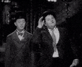 two men standing next to each other wearing suits and hats