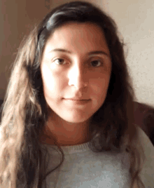 a woman with long brown hair is wearing a white shirt