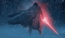 a person in a cape is holding a red light saber in the snow .
