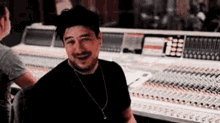 a man is sitting in front of a mixing desk in a recording studio .