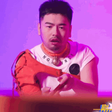 a man wearing a necklace that says nothing is holding a red object