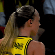 a female basketball player wearing a yellow jersey with the name emand on the back
