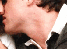 a man and a woman are kissing in a close up of their necks .