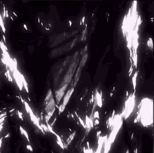 a black and white photo of a person standing in a dark room surrounded by flames .
