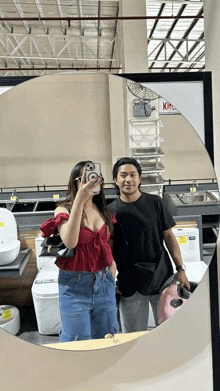 a man and a woman are taking a selfie in front of a mirror with a sign that says kitchen