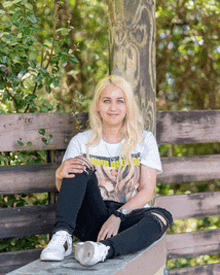 a woman is sitting on a bench with her legs crossed and wearing a white shirt that says nirvana