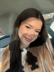 a woman with a nose ring is smiling while sitting in the back seat of a car
