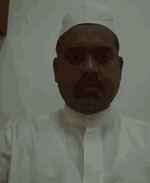 a man wearing a white hat and white shirt looks at the camera