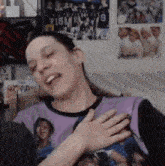 a woman wearing a purple shirt with the number 9 on it is sitting on a couch with her hands on her chest .