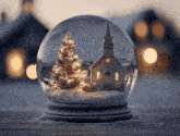 a snow globe with a church and a christmas tree in it
