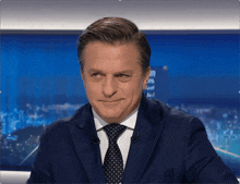a man in a suit and tie is smiling in front of a blue background