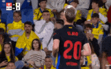 a soccer player with the number 20 on his jersey stands in front of a crowd