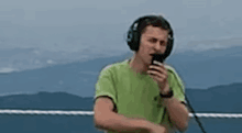 a man wearing headphones is holding a cell phone while dancing .