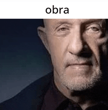 a close up of a man 's face with a beard and the word obra on the bottom .