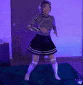 a woman in a striped shirt and a black skirt is dancing on a rug .