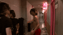 a man without a shirt is walking down a hallway with a pink sign that says c on it