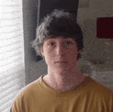 a young man standing in front of a window with blinds