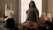 two women are standing next to each other in a living room in front of a window .