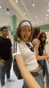 a woman wearing a headband and sunglasses laughs in a store