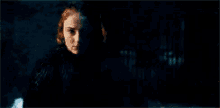 a woman is standing in a dark room with a candle in the background .